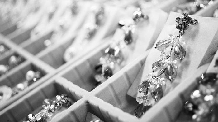 A showcase of diamond and precious gemstone earrings in black and white photography, backlit by soft light that sets the stones to sparkling.